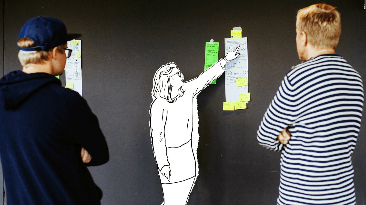Fra designsprinten: en deltager viser fram konseptskissen sin, som henger på veggen, mens de andre deltagerne lytter og observerer.